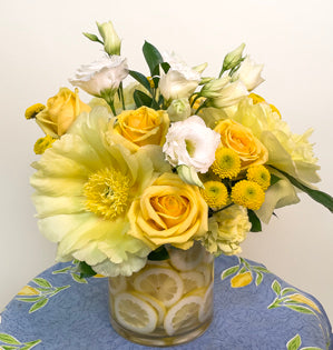 A refreshing design with a lemon vase, yellow tree peonies, roses, spray mums, ruscus and lisianthus.