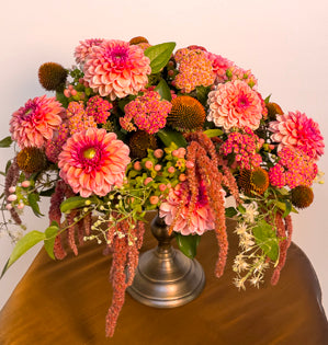 An elevated compote full of autumn blooms such as, dahlias, cone flower, hanging amaranthus, hypericum berries, cottage, yarrow, clematis vine, and ruscus.