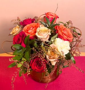 A beautiful bouquet made with ruscus, curly willow, pieris, and a variety of roses including golden mustard, freedom, mondial, and orange.