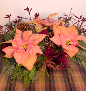 A large and lush design full of pine, douglass fir, and cedar evergreen foliage, carnations, kangaroo paw, cut poinsettias, and both ponderosa, and white pine cones.