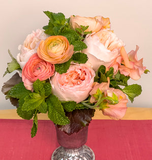 A small bouquet made with Juliet garden roses, ranunculus, sweet peas, thyme, mint, and galax leaves.