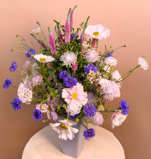 A whimsical vase design full of, eryngium, scabiosa, veronica, bachelor buttons, and cosmos.