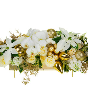 A luxurious gold and white centerpiece full of variegated holly, gilded cypress and seeded eucalyptus, carnations, stalk, roses, hydrangea, cut poinsettias, gold ornaments, topped with phalaenopsis orchids.